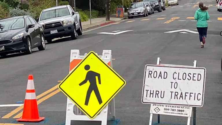 A woman running on a "Slow Street" that is closed to vehicle through traffic.