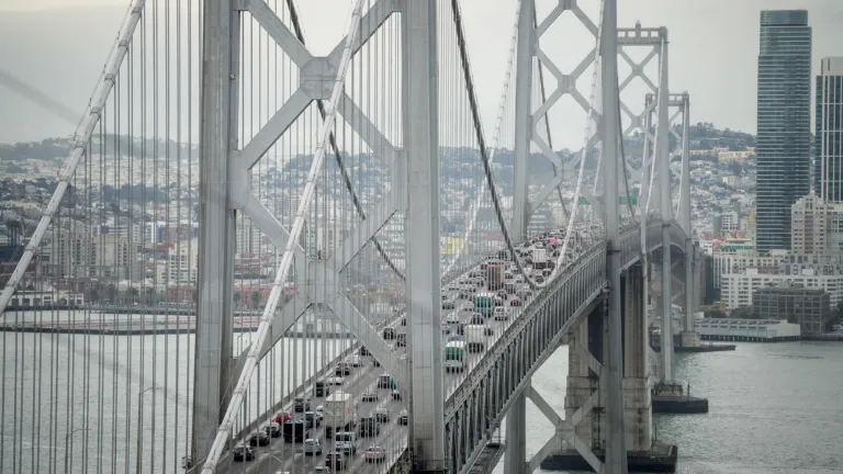 Cars travel west toward San Francisco on the upper deck of the Bay Bridge while SF's cityscape is in the background