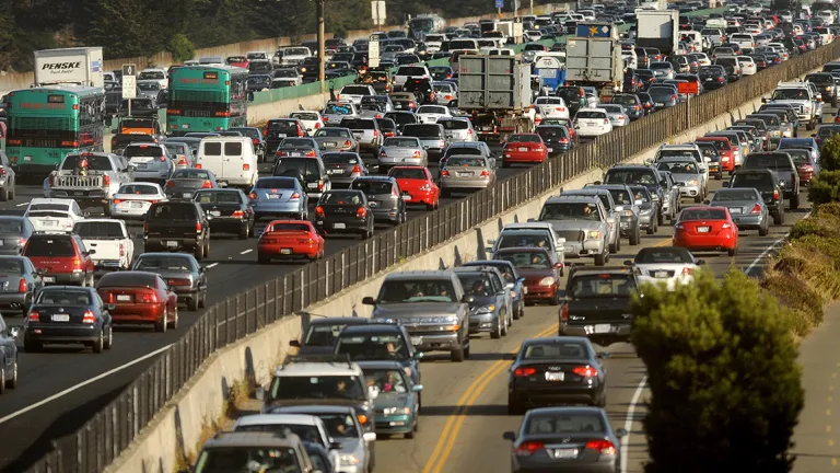 A runner jogs on a running path next to congested I-80