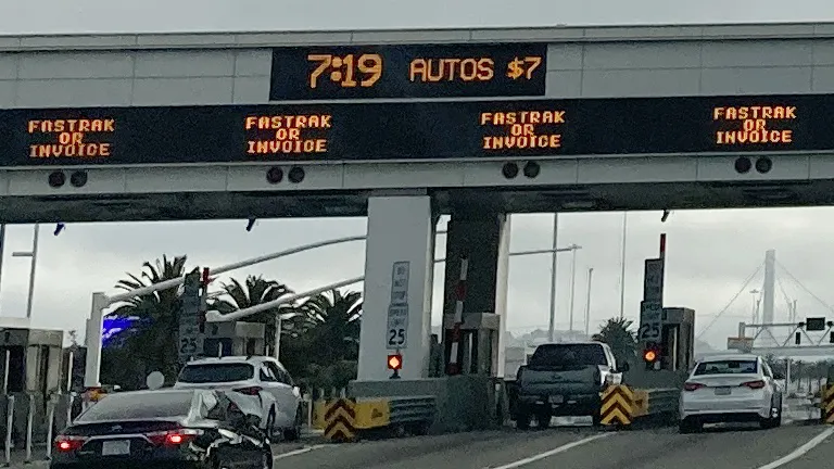 Electronic toll booth signs indicating the time, the price of a toll ($7), and FasTrak or Invoice.