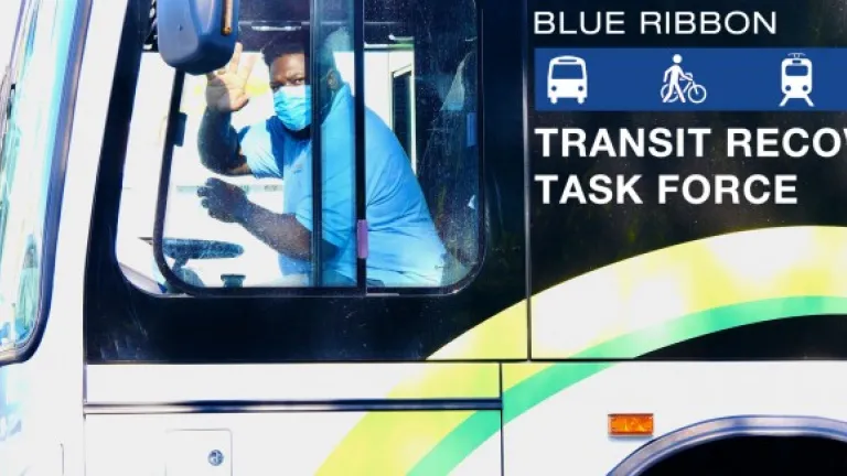 Bus driver wearing mask waves to camera