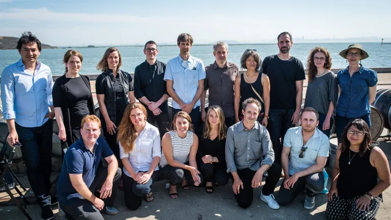 group of people posing for picture in front of water