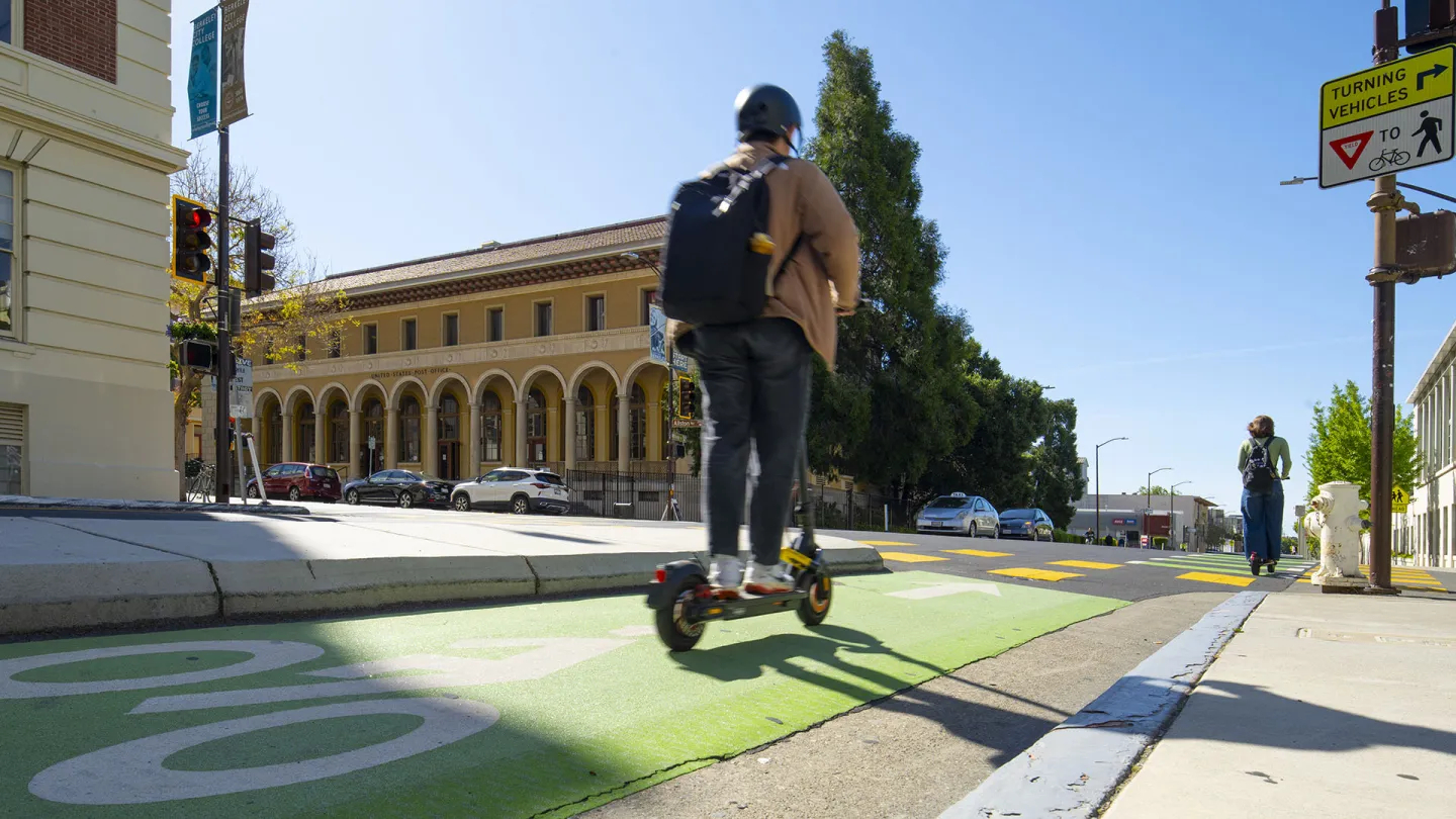 A person riding an electric scooter on a protected bike lane in Berkeley.