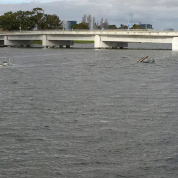 King tide at Coast Guard Island in Oakland. A boat sits sinking below the water, and the water level reaches nearly the underside of the bridge.