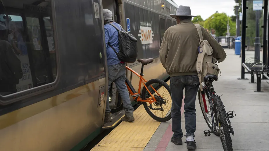Cyclists wheeling their bicycles onto a SMART train in Santa Rosa.