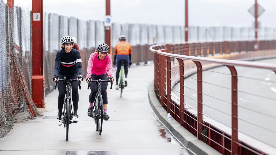 Cyclists crossing a foggy Golden Gate Bridge.