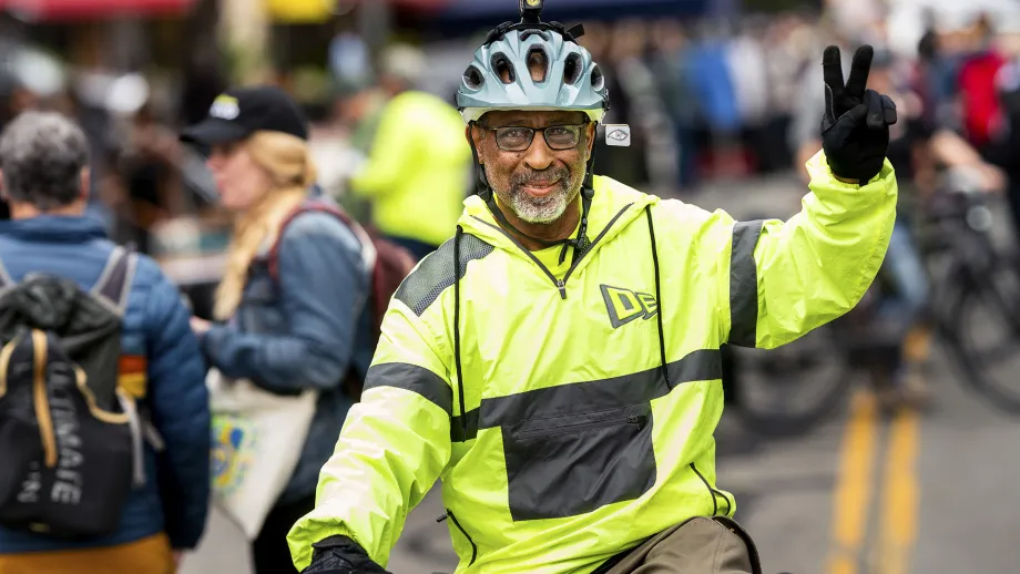 A smiling cyclist flashes a peace sign on Bike to Work Day.