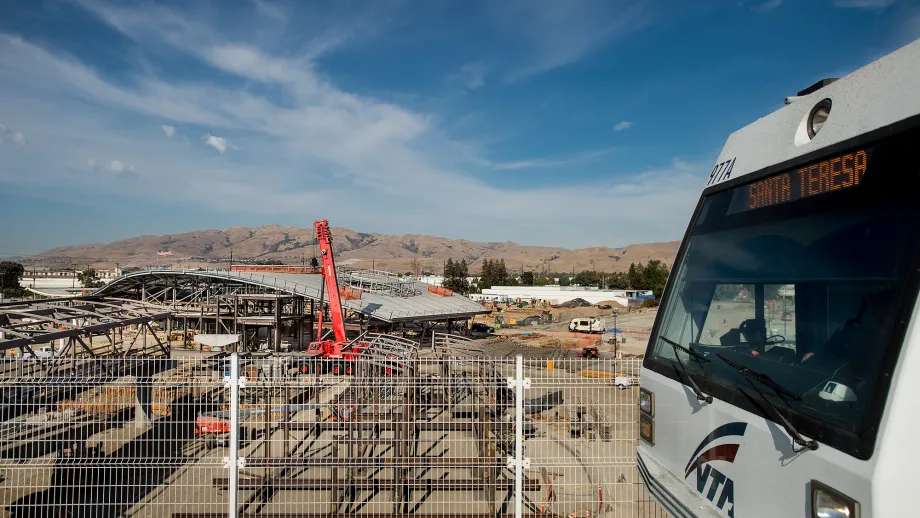 Light rail passes through Montague Station with Milpitas BART Station in background.