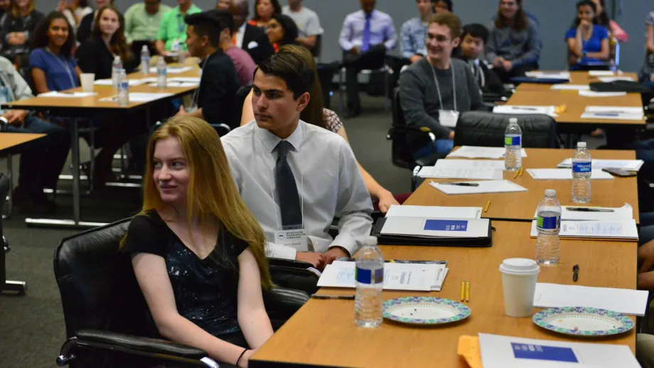 people sitting at tables listening to a speaker