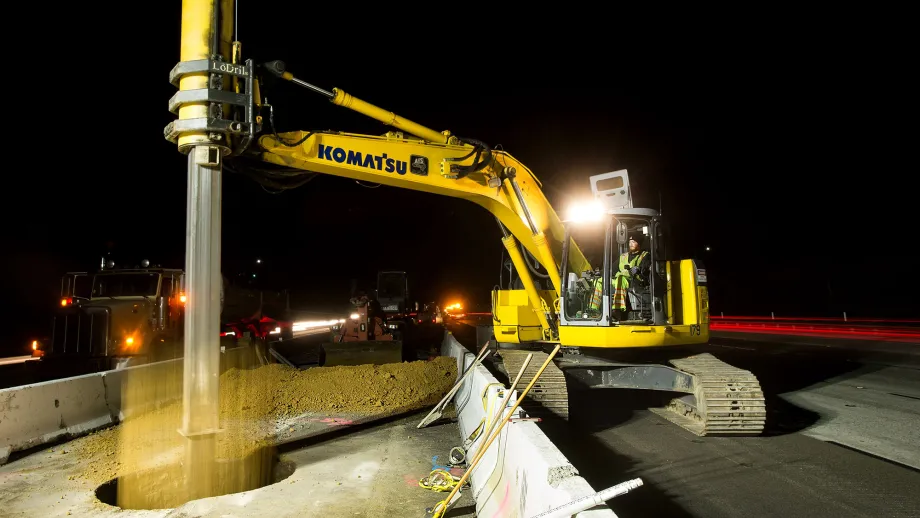 Construction crews use an excavator in pre-drilling activities for express lane sign foundations.