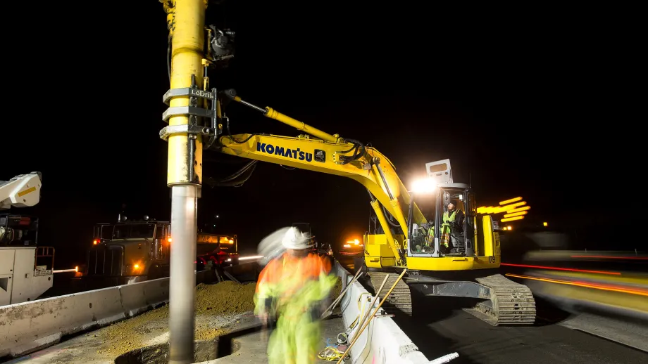 Construction crews use an excavator in pre-drilling activities for express lane sign foundations.