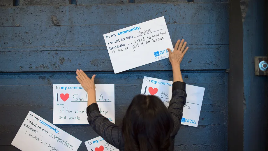 person pinning up a sign that reads I love my community because