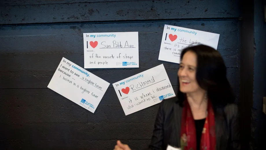 person pinning up a sign that reads I love my community because