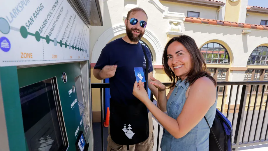 two people holding up card to get on train