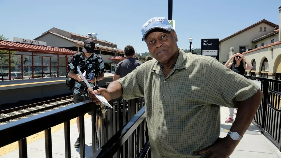 man leaning on railing at train station
