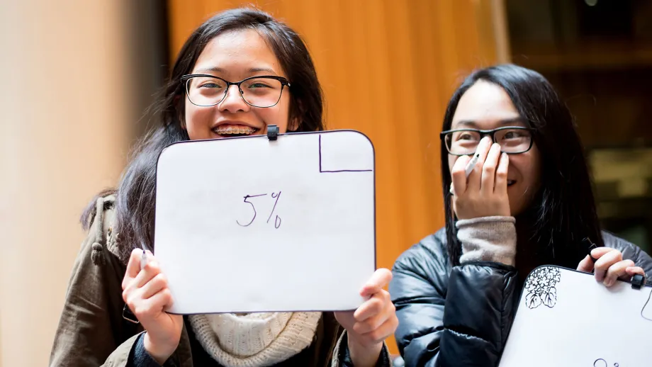 young adult holding up a dry erase board