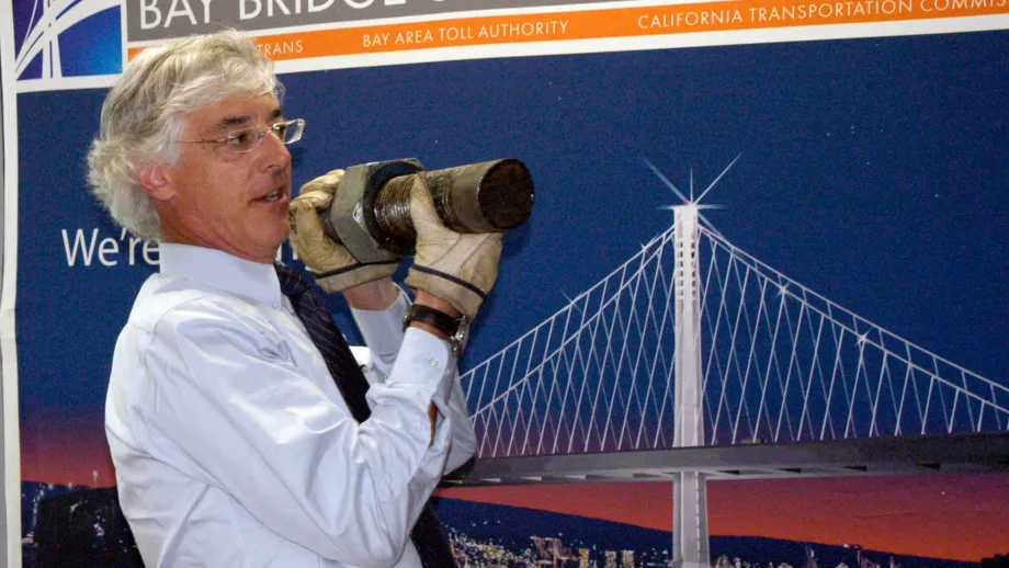 Dr. Brian Maroney, Caltrans' lead bridge engineer, holds up a piece of a three-inch diameter bolt at a post-BATA meeting press briefing.