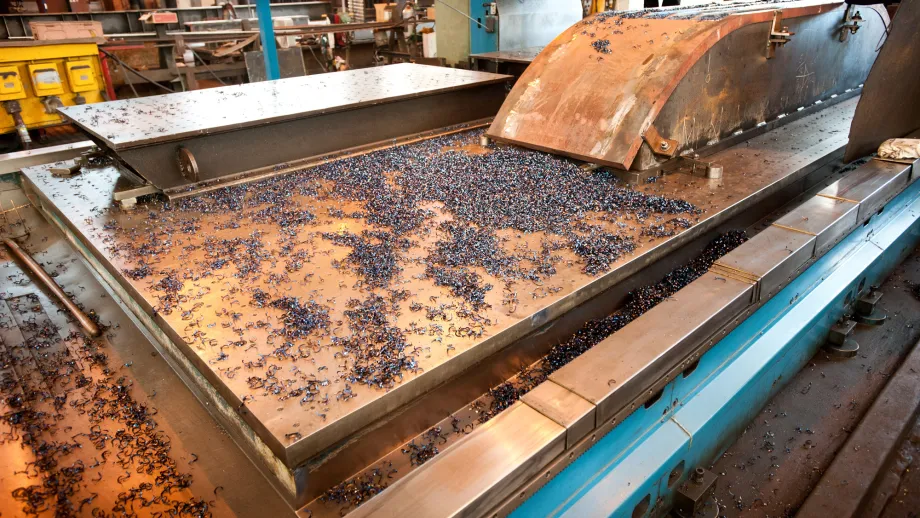 Shavings cover a table as a machine cuts a portion of the Bay Bridge's saddle, top right.