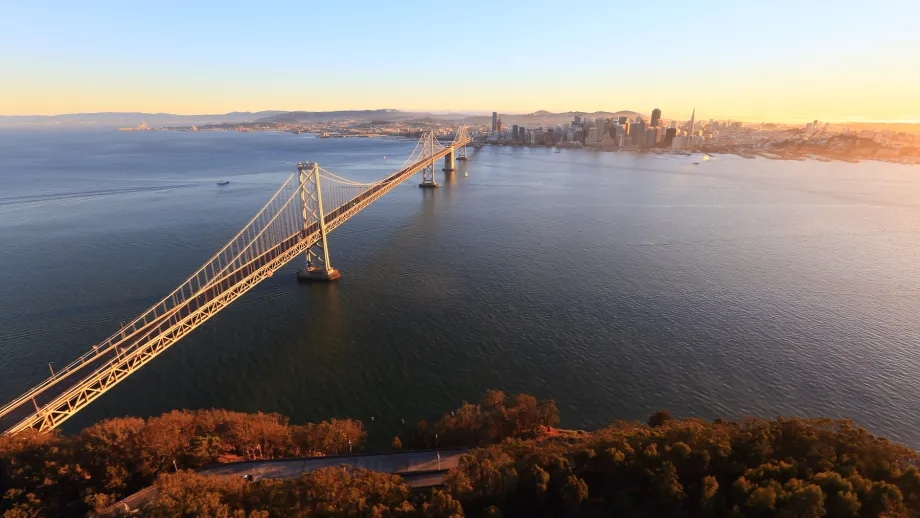 The West Span of the Bay Bridge stretches from Yerba Buena Island in the foreground to San Francisco in the background as the sun rises.