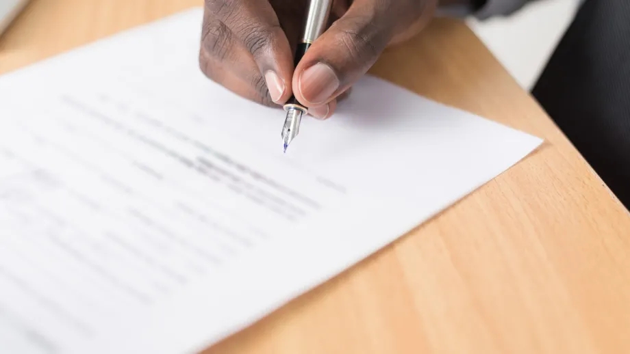 Man's hand signing document.