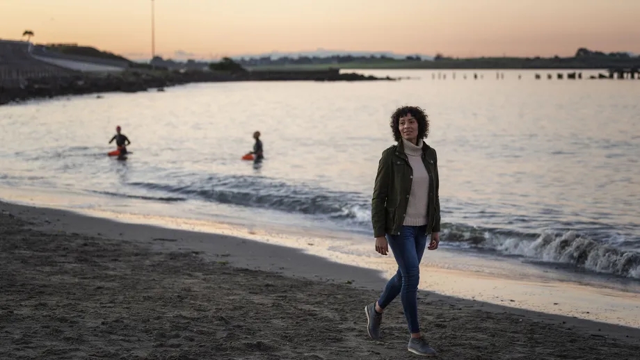 A person walks along the waves of the Bay Trail at sunset.