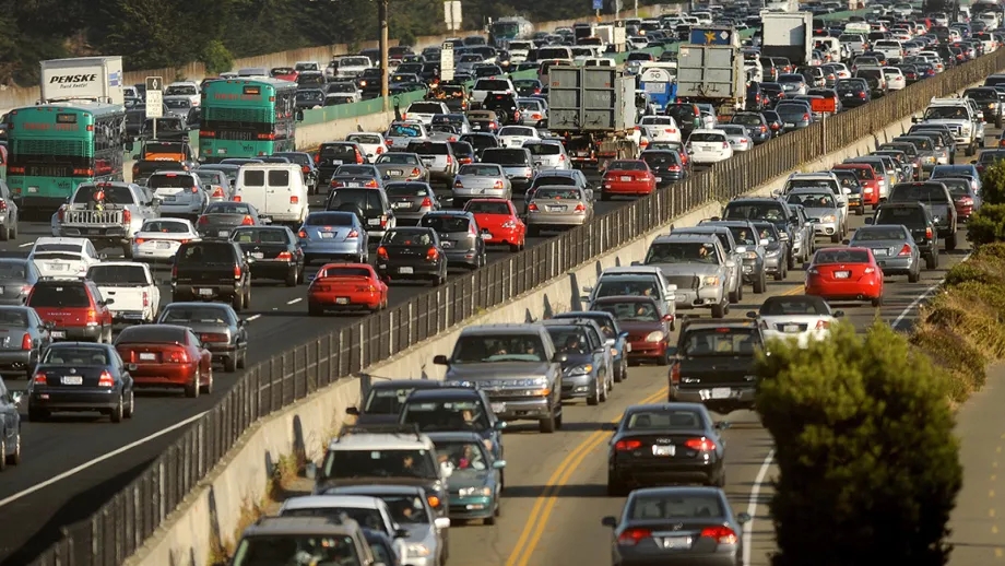 A runner jogs on a running path next to congested I-80