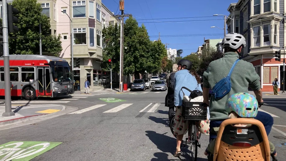 Cyclists waiting for a Muni bus to pass.