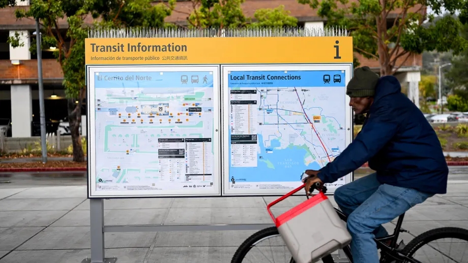 A cyclist rides past a new Transit Information sign at El Cerrito del Norte BART station.