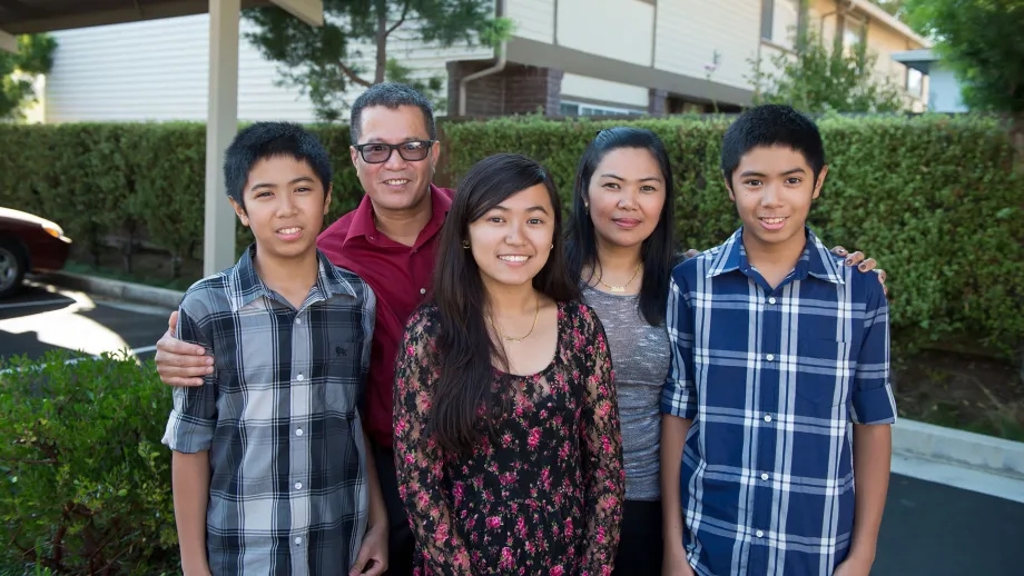 A happy family stands together in front of their home.