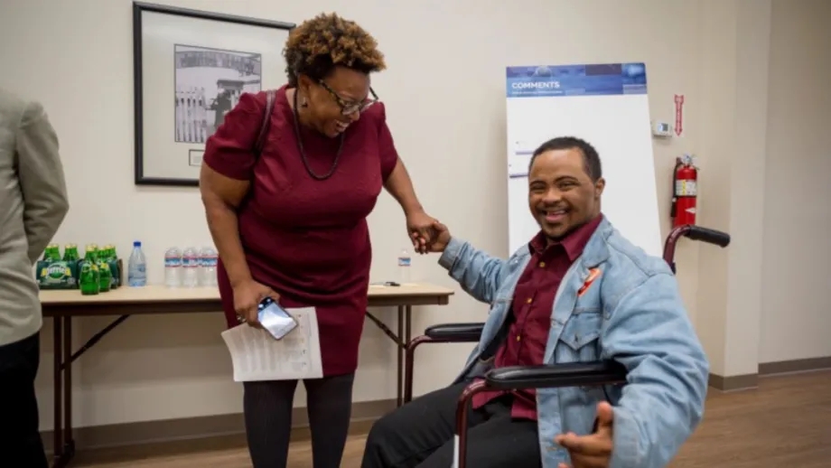 A smiling person in a wheelchair at a public engagement event.