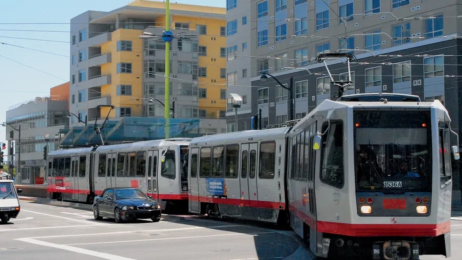 a Muni Metro streetcar glides past compact housing in San Francisco
